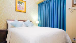 a bedroom with a large bed with blue curtains at Currency Serviced Suites in Manila