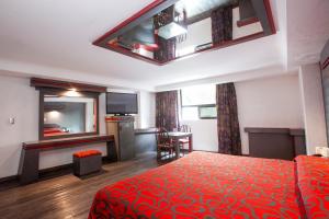 Habitación de hotel con cama roja y escritorio. en Hotel La Rosa - Sólo Adultos, en Ciudad de México