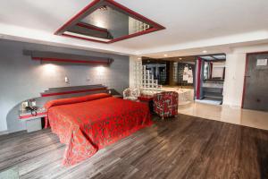 a bedroom with a red bed and a bathroom at Hotel La Rosa - S&oacute;lo Adultos in Mexico City