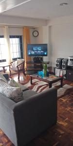a living room with a couch and a flat screen tv at Emiliez Place in Baguio