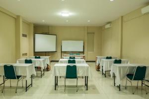 a conference room with tables and chairs and a screen at Hotel Cepu Indah 2 in Cepu