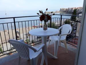 una mesa con 2 sillas y un jarrón con flores en el balcón en Casa Alba, en Cefalú