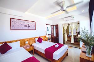 a hotel room with two beds and a living room at Riverside Plum Garden Villa in Hoi An +83 photos