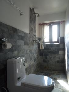a bathroom with a toilet and a brick wall at Good Hotel in Bandīpur
