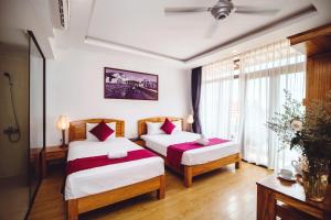 ein Hotelzimmer mit 2 Betten und einem Fenster in der Unterkunft Riverside Plum Garden Villa in Hoi An