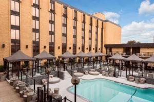 a hotel with a pool and umbrellas in front of a building at Wyndham Garden Dallas North in Dallas