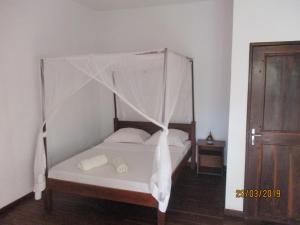 a bedroom with a bed with a mosquito net at Tropic Hôtel in Ambondrona