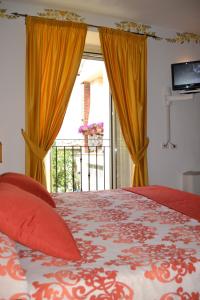 1 dormitorio con 1 cama con cortinas de color naranja y balcón en Il Cantuccio, en Poggio Murella