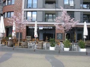 een restaurant met tafels en stoelen, parasols en bomen bij Comfortable Homly Apartment in Offenbach