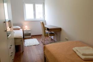 een slaapkamer met een bed, een bureau en een raam bij Apartments Mobine in Metković