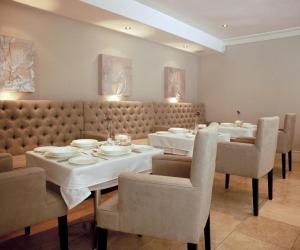 Banksia Boutique Hotel & Spa في كيب تاون: غرفة طعام مع طاولتين وكراسي