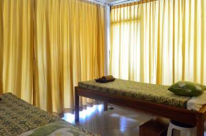 a room with two beds and a window with yellow curtains at RedDoorz Plus @ Raya Senggigi Lombok in Senggigi