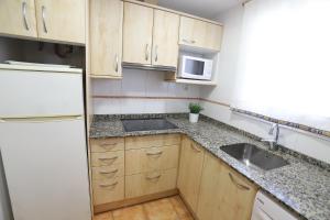 カンブリルスにあるCOSTA DAURADA APARTAMENTS - Regueralのキッチン(木製キャビネット、シンク、冷蔵庫付)
