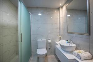 a bathroom with a toilet and a sink and a mirror at Aquamare Beach Hotel & Spa in Paphos