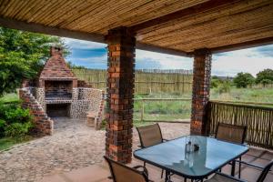 a patio with a table and a brick fireplace at Stone Hill in Magaliesburg