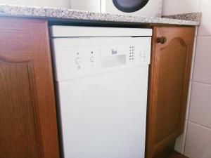 un lavavajillas blanco en una cocina junto a una barra en Apartament Boliera, en Espot