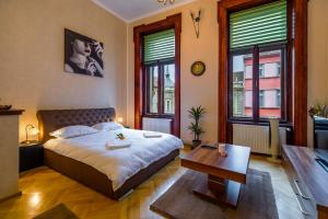 a bedroom with a bed and a table and windows at Select City Center Apartments in Braşov