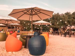een groep stoelen en tafels met parasols in het zand bij Aquamare Beach Camp Resort in Siquijor