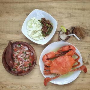 einen Tisch mit zwei Teller Essen und einer Krabbe in der Unterkunft Kimo Resort Pulau Banyak Aceh Singkil in Alaban