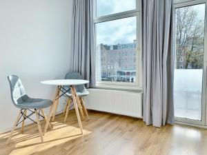 アムステルダムにあるJordaan Viewの椅子2脚、テーブル、窓が備わる客室です。