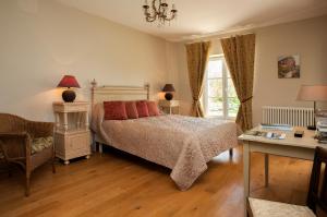 a bedroom with a bed and a desk and a window at Maison d'hôtes de Charme Les Bruhasses in Condom