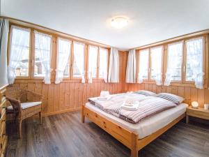 a bedroom with a large bed in a room with windows at Chalet Guttannen EG - GriwaRent AG in Guttannen