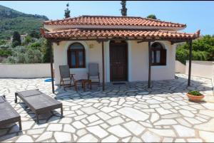 Casa pequeña con patio con mesa y sillas en Pleoussa Studio and Apartments, en Skopelos Town