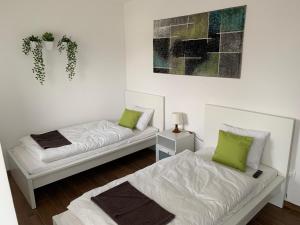 two beds in a white room with green pillows at Lili Motel in Sajószentpéter