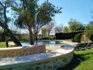 a swimming pool with a stone wall around it at Camping Pré-Fixe in Cassagnabère-Tournas