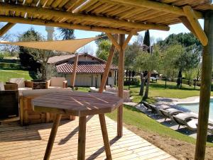 una terraza de madera con mesa y sombrilla en Camping Pré-Fixe, en Cassagnabère-Tournas