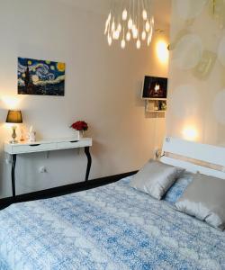 a bedroom with a bed and a table and a chandelier at My First Apartment in Budapest