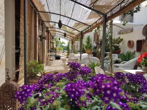 a patio with purple flowers and tables and chairs at A Lumia in Noto