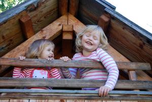 two little girls looking out of a window in a tree house at Familienbauernhof Glawischnig-Hofer in Gmünd in Kärnten