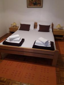een groot bed met witte lakens en kussens erop bij Apartmani Lončar in Novalja