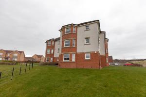 een groot bakstenen gebouw op een grasveld bij Super Prime Duloch - Dunfermline - 2 Bed Executive Apartment in Dunfermline