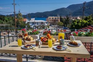 een houten tafel met ontbijtproducten op een balkon bij House of Hats - next to the coast - Karavomylos in Karavomylos