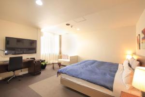 a bedroom with a bed and a desk and a television at Hotel Tohkai in Atsugi