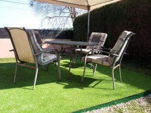 4 sillas y una mesa con sombrilla en la hierba en Casita de Folgosa, en Ribadeo