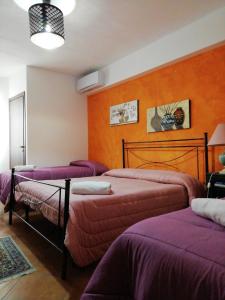 una camera con tre letti con lenzuola viola di Bed and breakfast Agrumi in terrazza ad Aragona