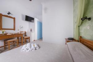 a bedroom with a bed with two pairs of slippers at Hotel Olympia in Karterados