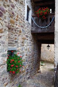 a stone building with a balcony with flowers on it at Casa Vacanze di Arlecchino in San Giovanni Bianco