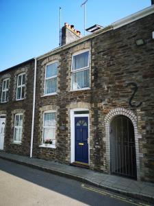 um edifício de tijolos com uma porta azul numa rua em QUILLET COTTAGE, 2 GLENTOWAN ROAD em St Austell
