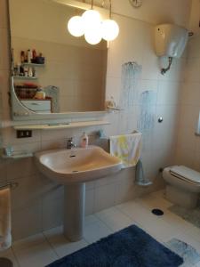 een badkamer met een wastafel, een toilet en een spiegel bij Appartamento in villa Virginia in Mondragone