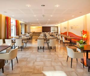 a dining room with tables and white chairs at Logis Hotel Restaurant Muller in Niederbronn-les-Bains