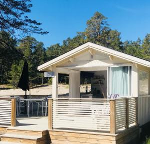 Ce mobile home dispose d'une terrasse couverte et d'une table. dans l'établissement Hölick Havsresort & spa, à Hudiksvall