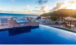 a large swimming pool with the ocean in the background at Sonia Flats 214 - Flat privado no Apart Hotel Pipa's Bay in Pipa