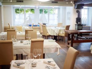 a restaurant with white tables and chairs with wine glasses at Landgasthof Ochsen in Wölflinswil