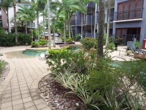 a resort with a swimming pool and palm trees at Jackies City Central Apartment in Cairns