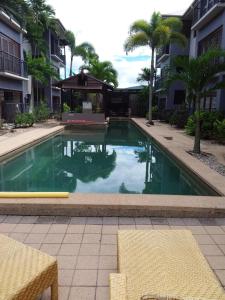 a swimming pool in front of a building with palm trees at Jackies City Central Apartment in Cairns