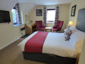 a hotel room with a bed and two red chairs at The Brevins Guest House in Fort William